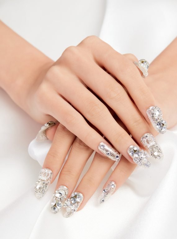 A vertical shot of a female's hands with diamonds on the nails